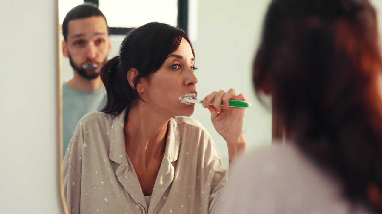 Casal escovando os dentes em frente ao espelho do banheiro