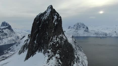 drone view in tromso area in winter flying over a snowy mountain showing segla rocky peak in segla, norway