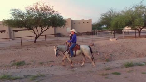 cowgirl horseback riding at sunset in the arizona desert