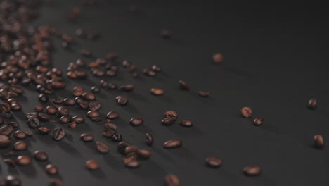 Slow-motion-footage-of-coffee-beans-falling-onto-black-surface