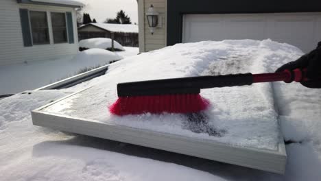 someone brushing snow off of a solar panel that is mounted on top of an suv at half speed