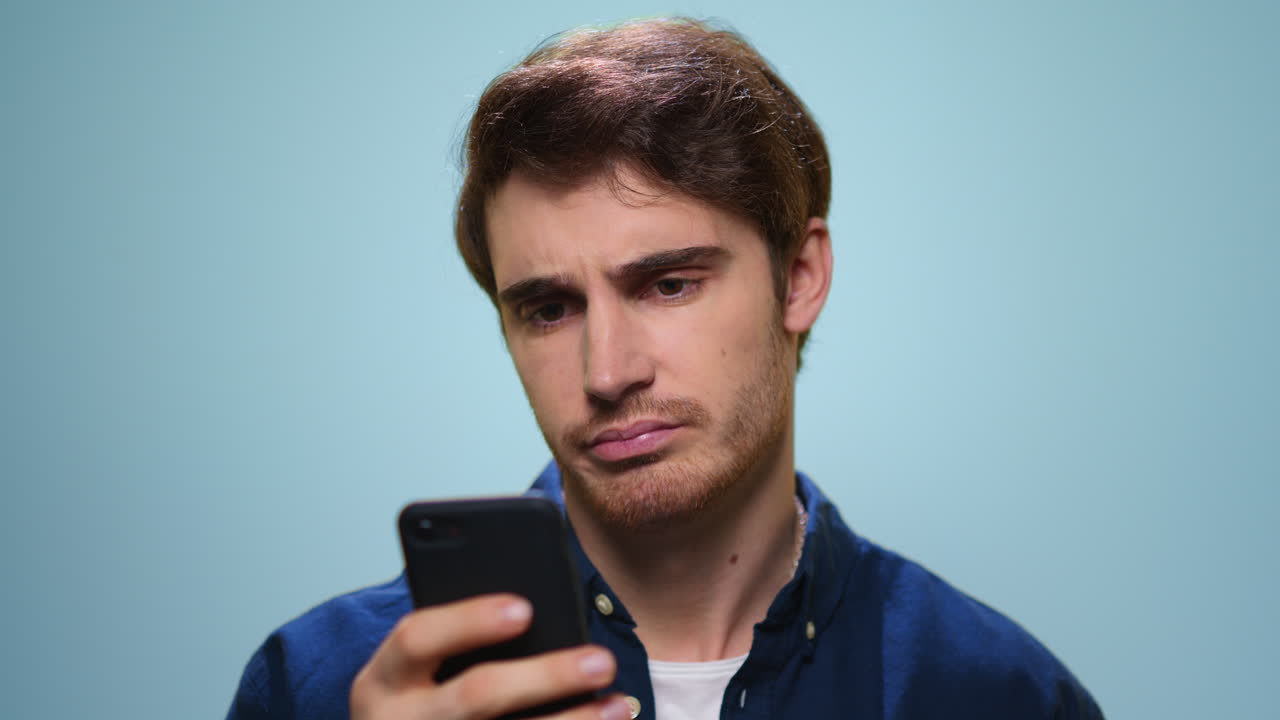 Homem chateado lendo más notícias no smartphone. Homem triste usando o telefone no estúdio