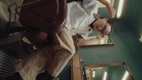 asian man brushing hair and posing for camera in barbershop