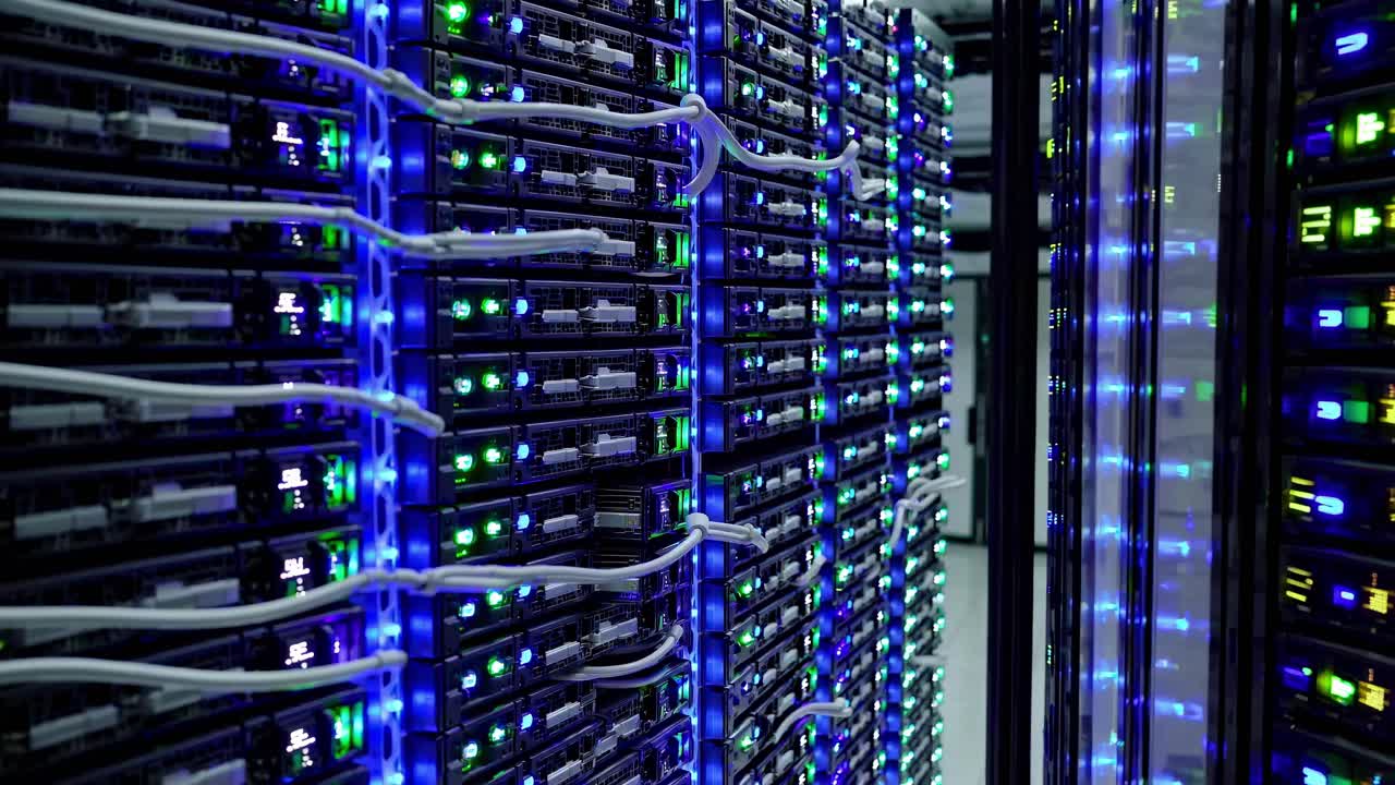Wide-angle shot of a data center with rows of servers, glowing lights, and cables