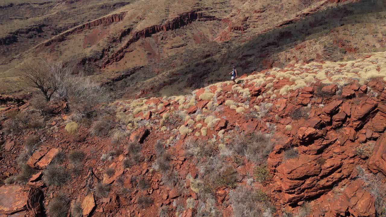 fotografía de avión no tripulado de un excursionista solitario en las montañas del desierto rojo en el parque nacional australiano en verano - cámara lenta
