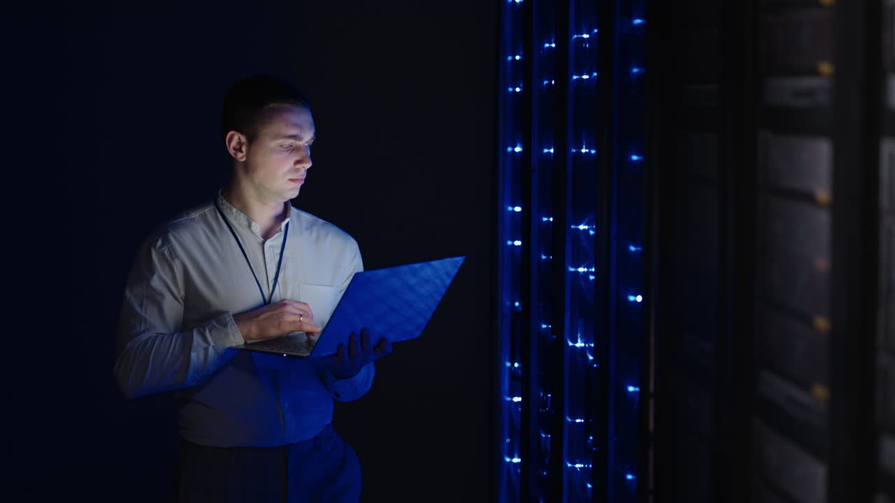 The Concept of Digitalization of Information: IT Specialist Standing In front of Server Racks with Laptop He Activates Data Center with a Touch Gesture. Network Data