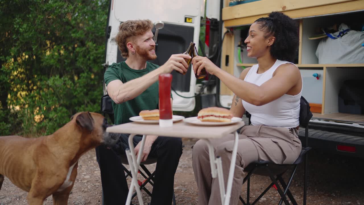 Couple enjoying food and drinks outdoors with their dog
