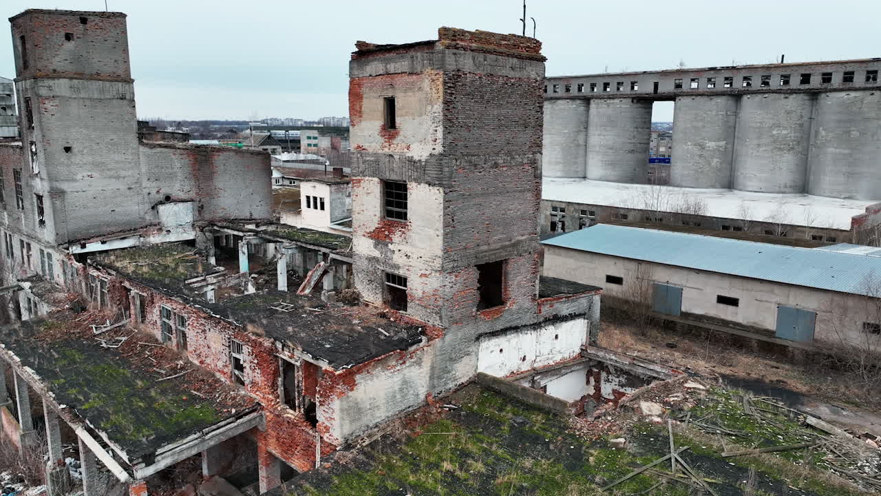 Industrial area destroyed and devastated by time. Old wrecked plant premises ready for demolition. Excavators at the backdrop.