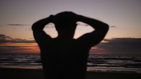 silhouette man holds head facing sunset sea in slow motion conveying stress and search for inner peace