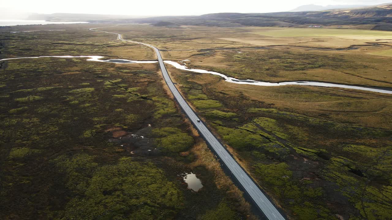 abajo de un coche que conduce por una larga carretera en un hermoso paisaje islandés