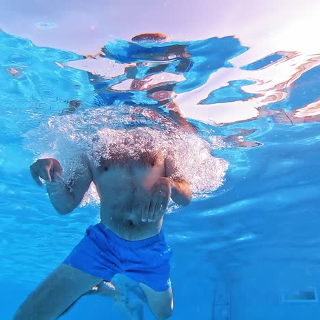 handsome young man swimming in pool, underwater view