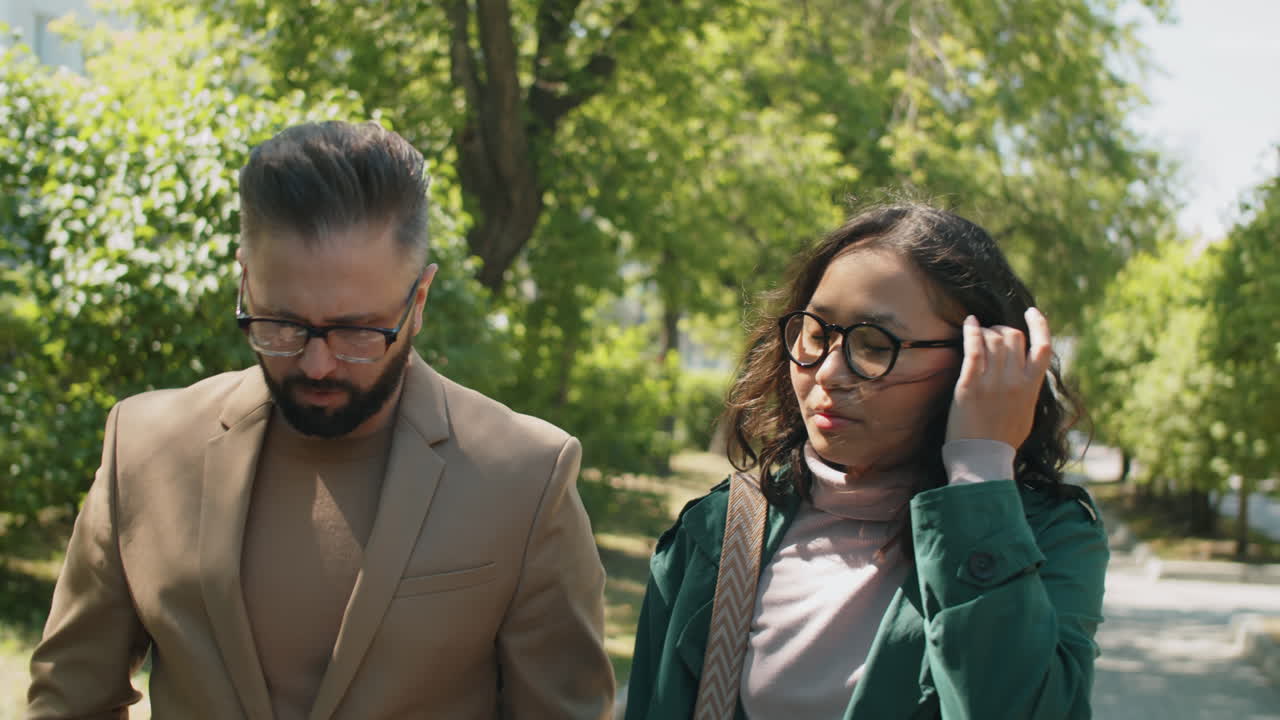 hombre y mujer multiétnicos caminando por el parque y hablando