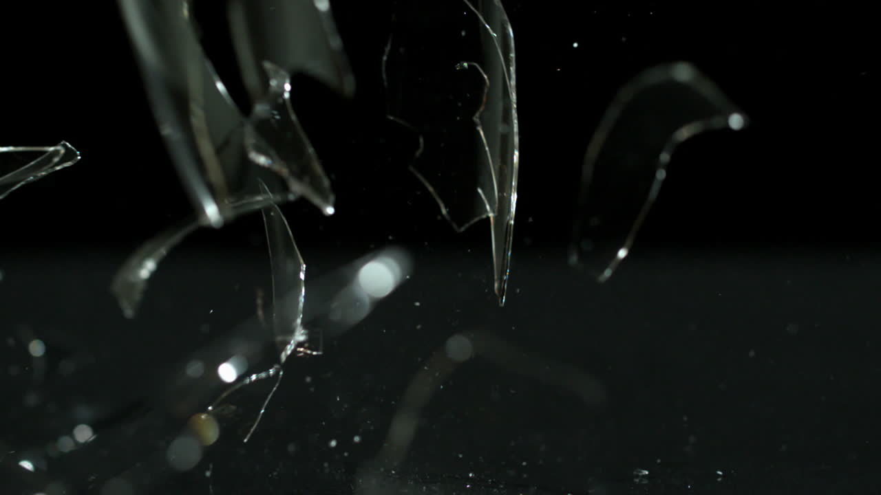 Wine glass falling and breaking on black background