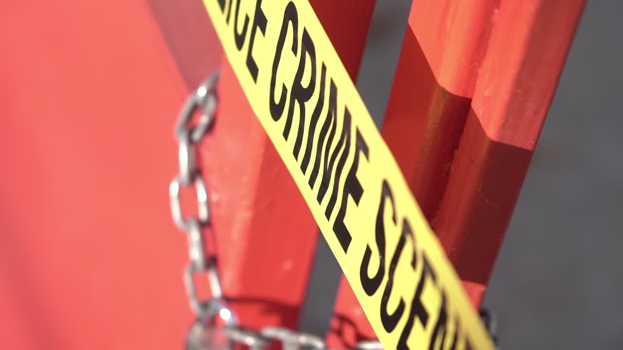 Crime Scene Police Tape on Metal Door With Lock and Chain, Close Up