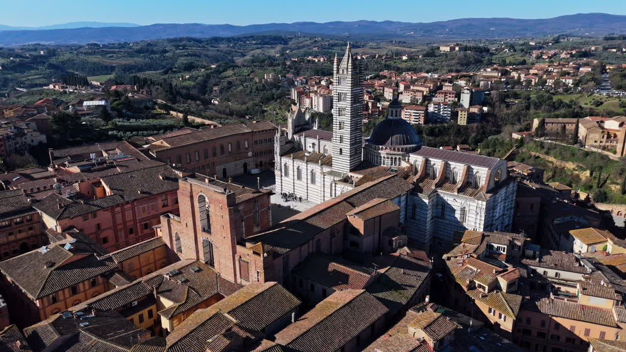 Historic aerial view of Duomo di Siena with terracotta rooftops and scenic hills