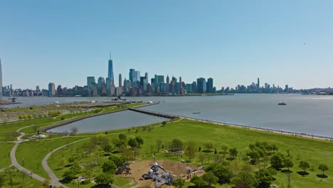 aerial panorama shot showing green grass of liberty state park and skyline of new york city in background in summer