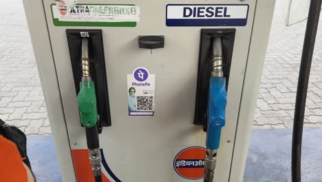 indian oil petrol pump, static shot of guy putting the pump nozzle, and picking up the bag, with the phonepe qr code pasted for the upi cash less payment option