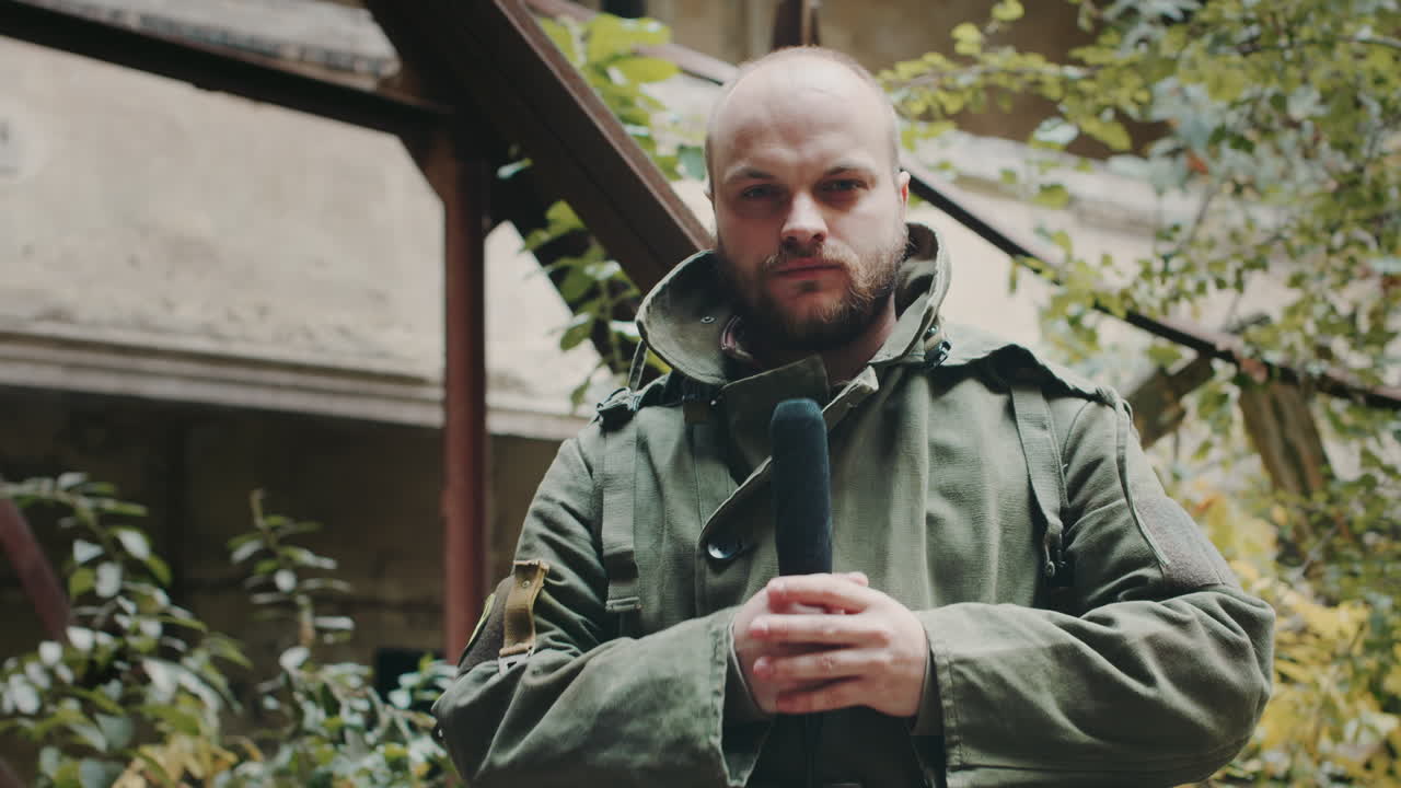 기자는 오래된 폐허가 된 건물 유엔군 보호복에서 보도하고 있습니다.