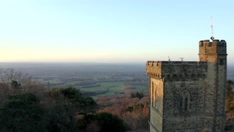 Glatte-Drohnenaufnahmen-Aus-Der-Luft,-Die-Am-Leith-Hill-Tower-In-Den-Hügeln-Von-Surrey-In-Der-Englischen-Landschaft-Vorbeifliegen