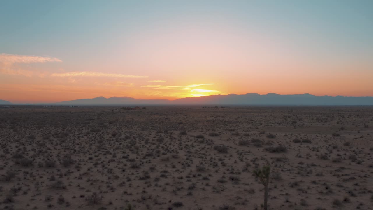 volando hacia atrás a través de la llanura del desierto de mojave durante la colorida puesta de sol, antena