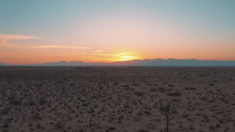 flying backward through mojave desert plain during colorful sunset, aerial