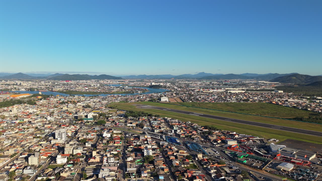 View of Navegantes Airport beside a riverside neighborhood in Brazil’s scenic landscape