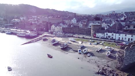 idyllic conwy castle and harbour fishing town boats on coastal waterfront aerial push inland slowly