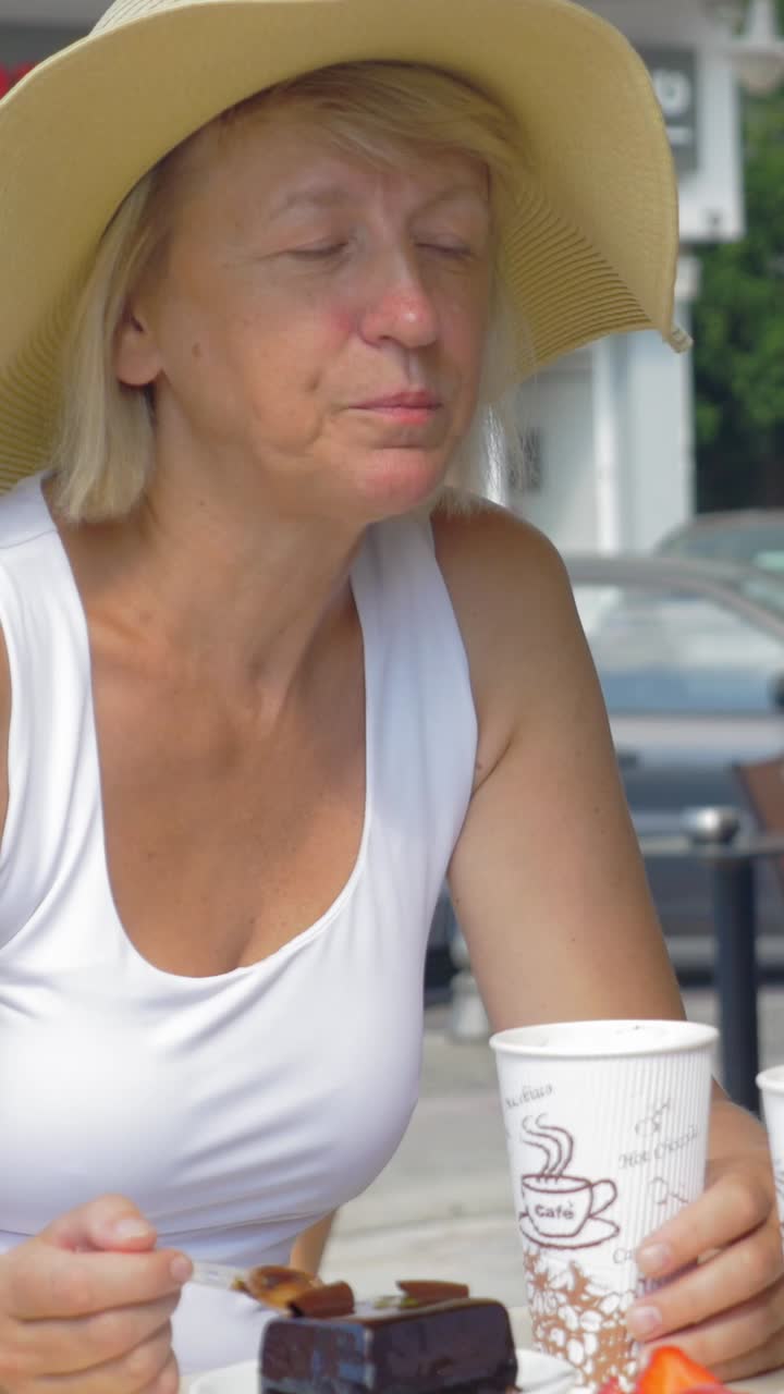 Woman with hat eating cake and drinking coffee