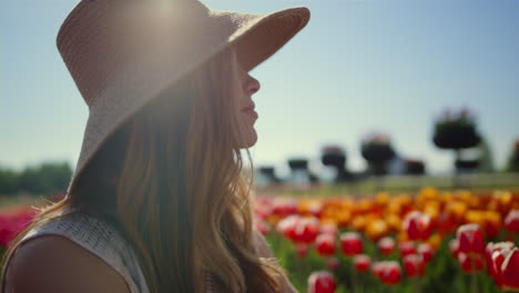 modelo posando en el campo de flores de primavera en el sol brillante. perfil de mujer en sombrero de sol.