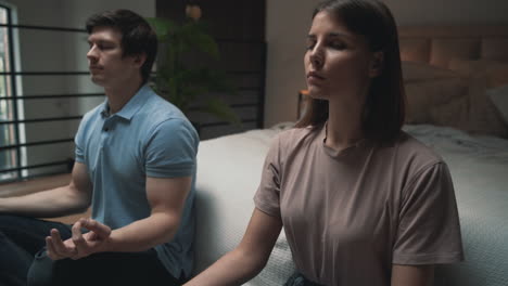 young couple meditating, woman and man sharing moments in lotus posisiton indoors