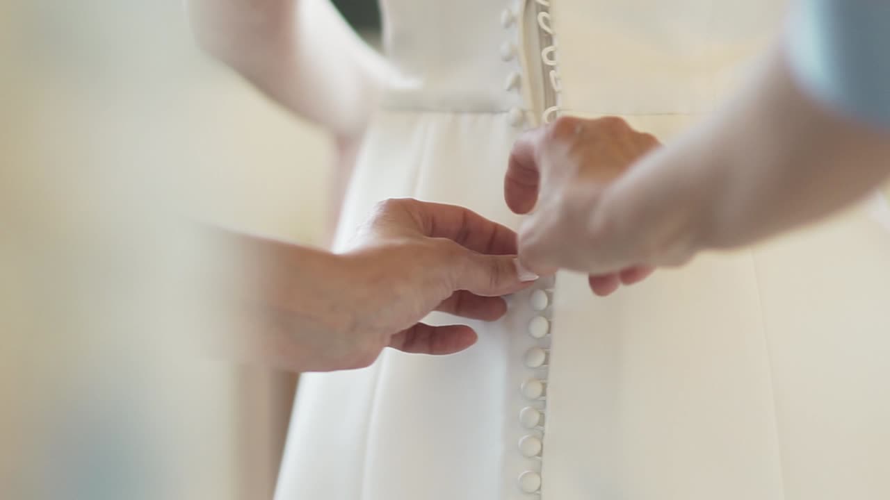 Person hands buttoning corsage on bride