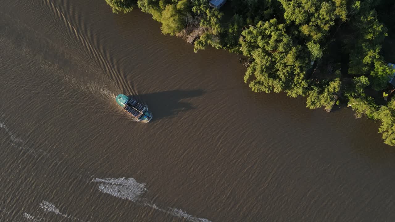 Aerial birds eye shot of Brazilian Cargo Ship transporting wood trunks on calm Amazon River during sunset