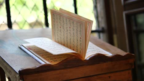 closeup of a quran open on a wooden stand