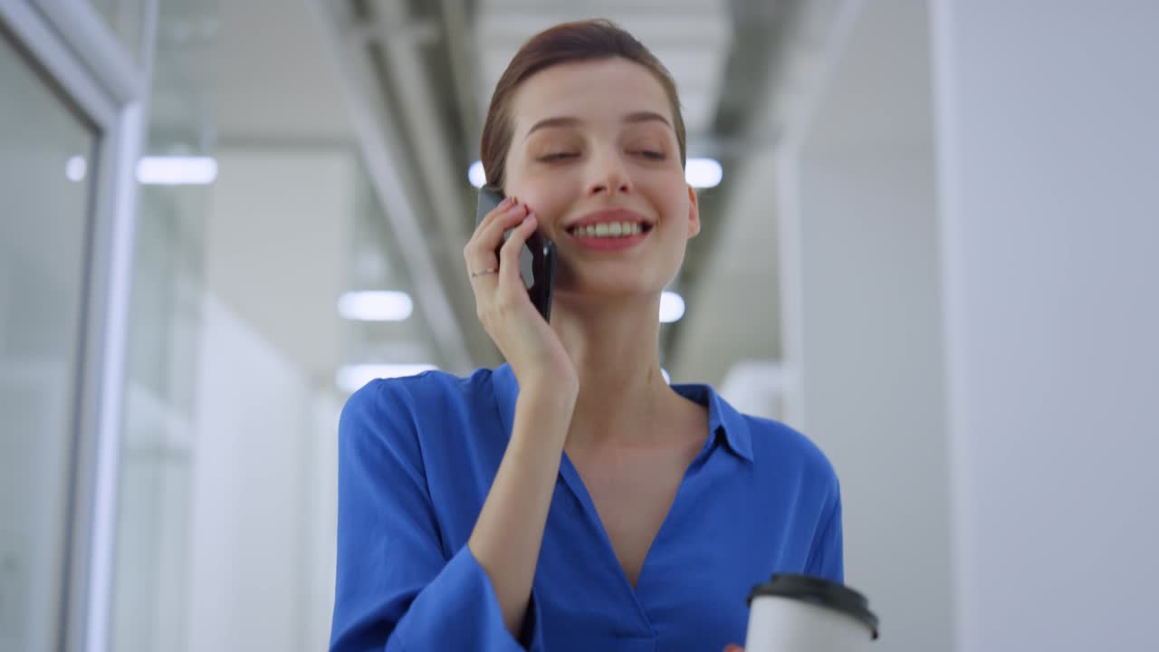 mujer de negocios alegre usando teléfono inteligente en el interior