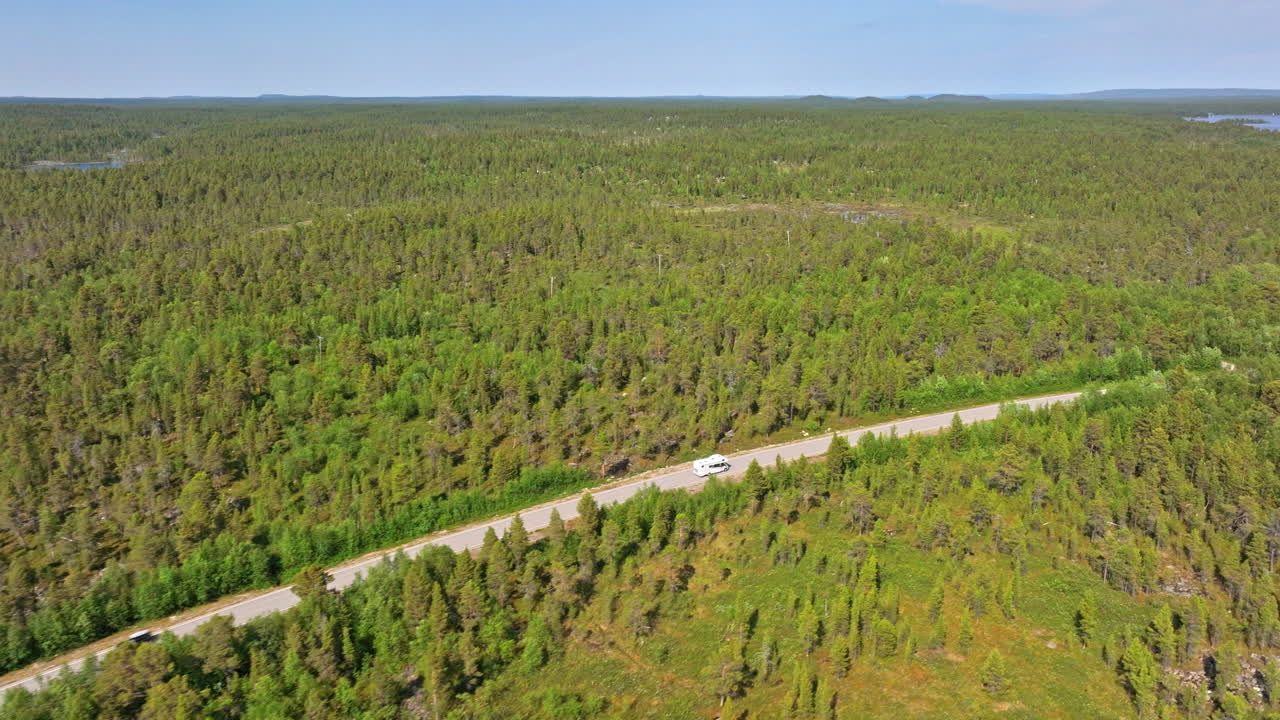 aerial: campista conduciendo en un camino boreal en medio de la interminable selva de laplandia