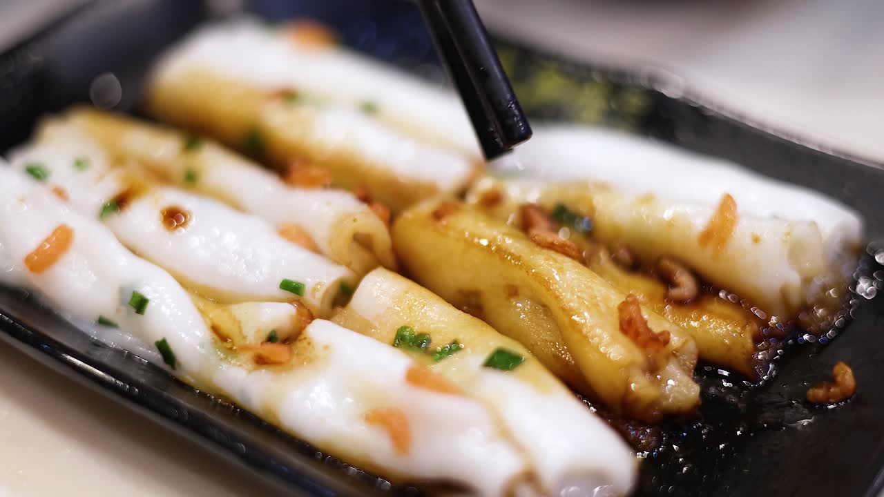 палочки для еды поднимают рисовые макаронные рулоны с соусом