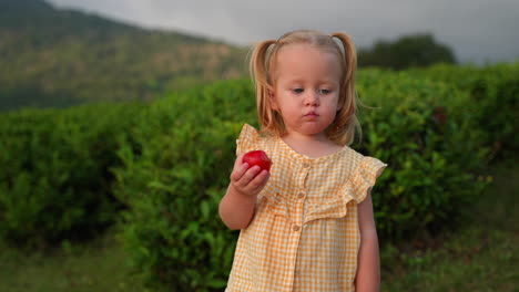 adorable toddler with red fruit in a tea plantation