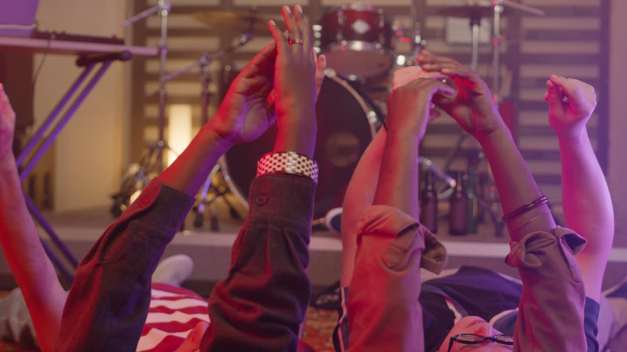 Close Up Of Unrecognizable Multiethnic Friends Moving And Clapping Their Raised Hands While Lying On The Floor During Rehearsal In Recording Studio