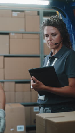 woman working in a warehouse, managing inventory with a tablet and headset