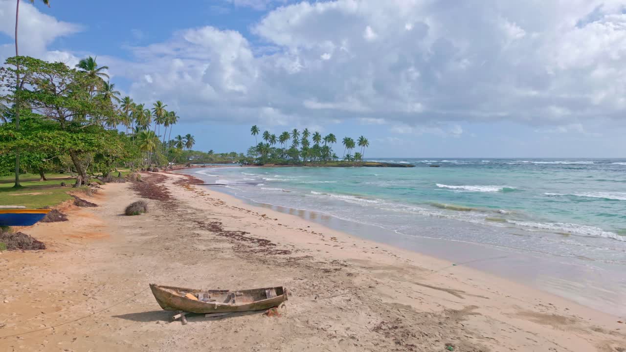 vuelo aéreo lento sobre la playa de arena de playa los coquitos con árboles tropicales, botes y mar caribe azul