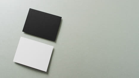 close up of two stacks of black and white business cards on grey background, copy space, slow motion