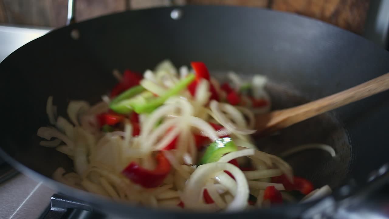 Primo piano di verdure saltate in padella colorate nel wok, mescolando con un cucchiaio di legno