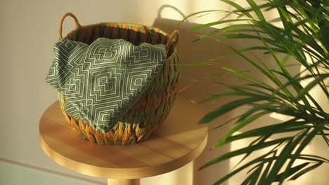 woven basket with green blanket and houseplant on a wooden stool