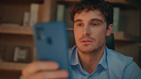 serious guy reading sms on smartphone at night home closeup. focused businessman