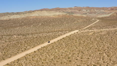 Todoterreno-Negro-Oscuro-Conduce-Por-Un-Camino-Recto-De-Tierra-Que-Atraviesa-Un-Paisaje-Desértico-Abierto