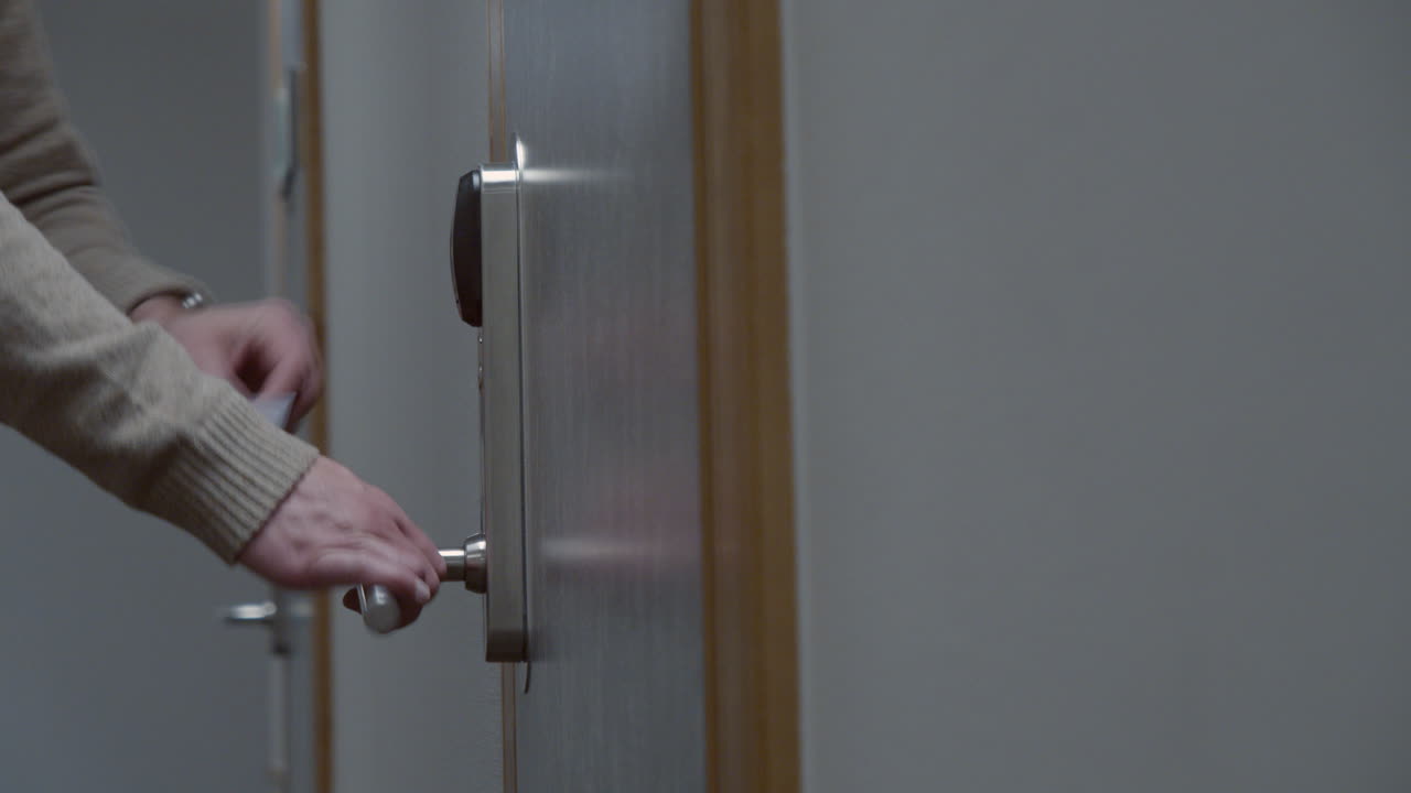 남자는 호텔 방에 접근하고 잠금을 해제하고 문을 열고 들어갑니다.