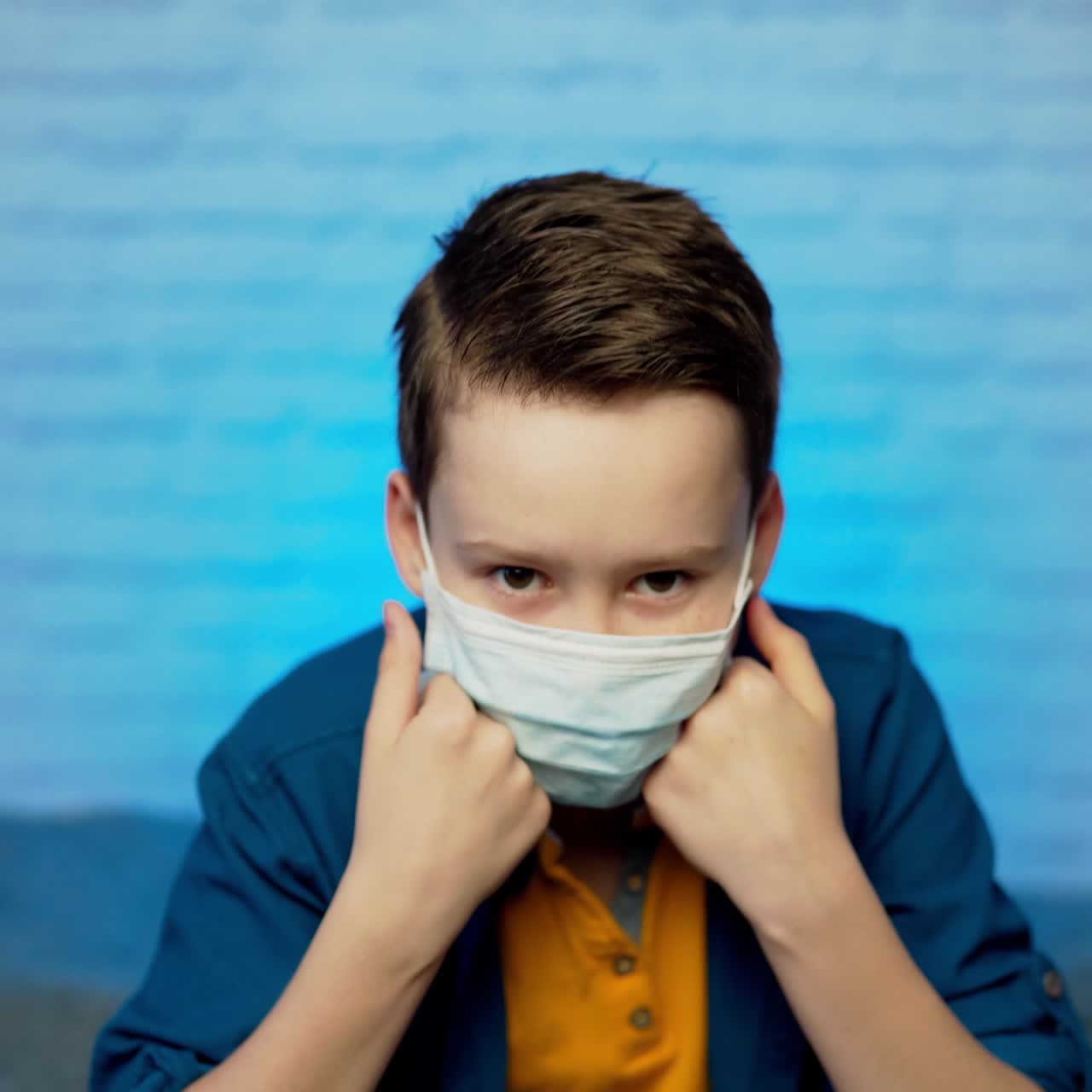 Beautiful boy puts on face medical mask against bacteria and viruses. Pandemic Covid-19. Quarantine in children. Self isolation