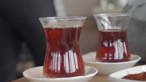 closeup of a glass of turkish tea being poured into a glass on a table