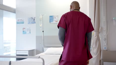 Besorgter-Afroamerikanischer-Arzt-Sitzt-Auf-Dem-Bett-Im-Krankenhauszimmer,-Zeitlupe