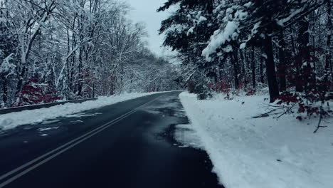 car driving on snow-covered mountain road in winter